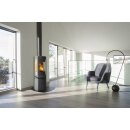 Der Jotul F378V2 Advance ist in einem weißen Raum zu sehen. Davor liegt eine schwarze Stahlplatte und in der Ecke des Bildes steht ein Sessel mit einer modernen Lampe.