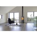 Der Jotul F378V2 Advance ist in einem Raum mit einer schrägen Decke zu sehen. In der Mitte des Raumes stehen ein Sessel und eine Lampe auf einem Teppich. Eine Stahlplatte steht unter dem Kaminofen.