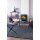 Der Kaminofen Jotul F 400 ECO steht in einem lilafarbenen Raum, mit einer Stahlplatte darunter. Links an der Wand hängen Regale mit Büchern und Dekorationen. Ein Couchtisch und Sessel stehen vor dem Kaminofen.