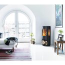 Morsoe 7443 Holzfach steht im dunklem Schlafzimmer. Der Ofen brennt und der Feuer beleuchtet die Zimmer. Links von der Ofen sieht man ein Bett und einem Fenster, zur Rechts kann man eine Poster und ein Tisch sehen.